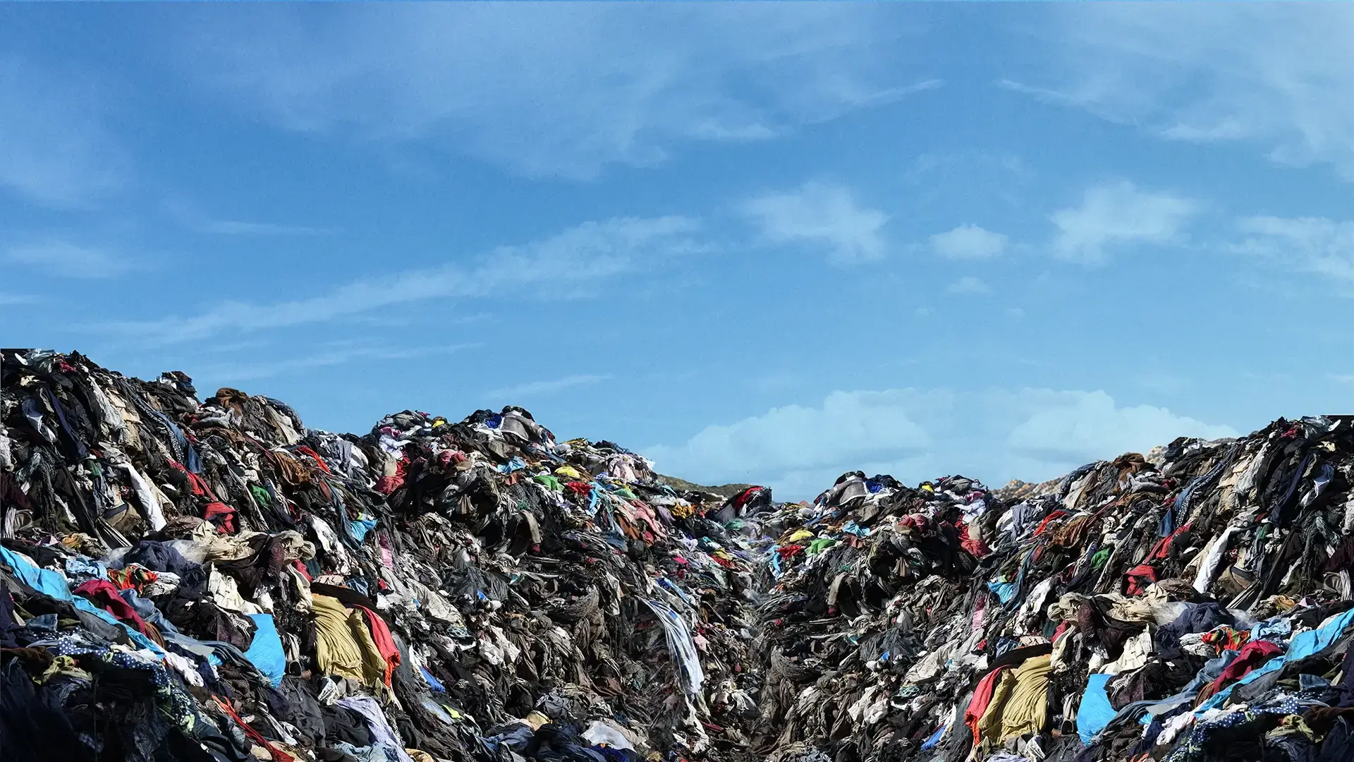 Textile waste landscape showing piles of discarded clothing and fabrics